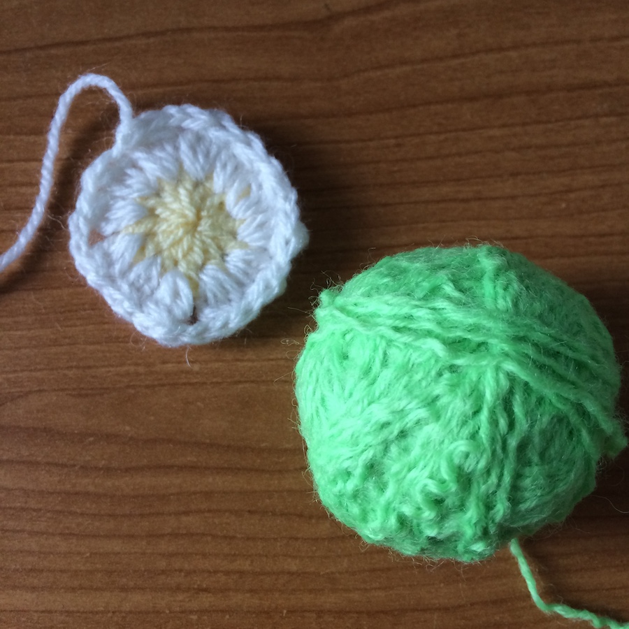 Crocheted daisy and ball of salvaged green yarn